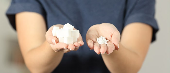 woman holding sugar cubes and sweeteners
