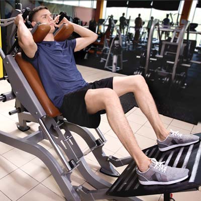 Man doing Machine Squat variation on a gym machine