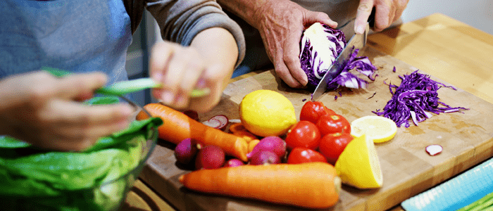 two people cutting up vegetables for a meal