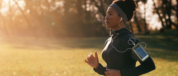 woman running in the sun listening to music