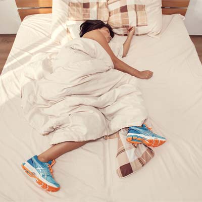 woman asleep in bed with trainers on ready for some morning exercise