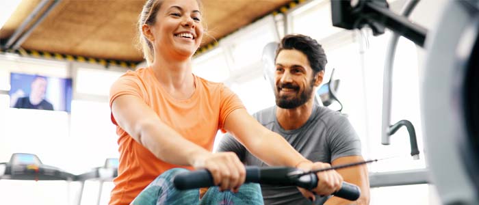 woman on a rowing machine being encouraged by a man