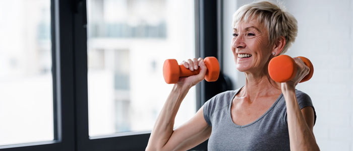 older woman lifting dumbbells to boost metabolism