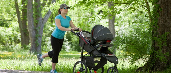 woman walking through the park with a pram/stroller