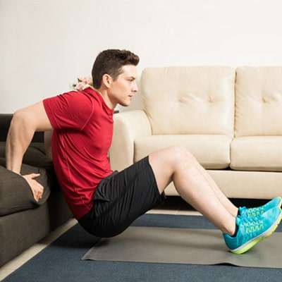 person performing a triceps dip on a sofa
